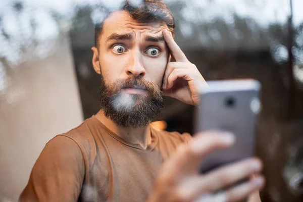 Sersemlemiş erkek yönetici akıllı telefonda kötü haberleri alıyor, ekranda dehşet verici bir ifadeyle bakıyor, sms mesajını okuyor, sureyi ifade ediyor. Hızlı internet 5g, reaksiyon, şok ve teknoloji konsepti