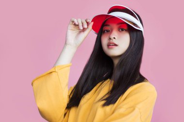 pembe arka plan üzerinde kırmızı kap dokunmadan sarı kazak asyalı kız