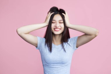 pembe arka plan üzerinde baş dokunmadan gülümseyen asyalı kız