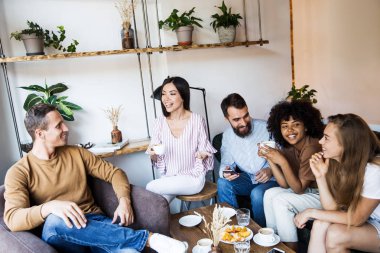 Modern bir kafenin iç mekanlarında oturan, birlikte eğlenen, kahve içen ve eğlenen bir grup genç