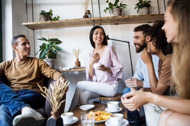 Modern bir kafenin iç mekanlarında oturan, birlikte eğlenen, kahve içen ve eğlenen bir grup genç