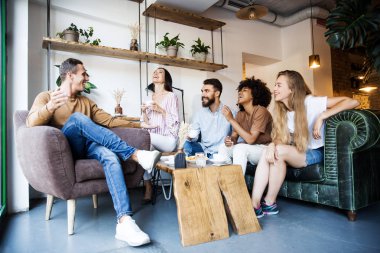 Modern bir kafenin iç mekanlarında oturan, birlikte eğlenen, kahve içen ve eğlenen bir grup genç