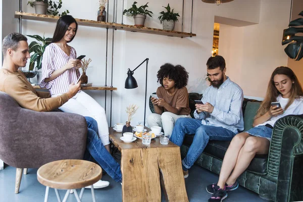 Multi Ethnic Group Young Friends Sitting Phones Table Modern Cafe — Stock Photo, Image