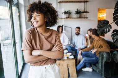 Modern ofistepencerenin yanında güzel genç bir kadın. Arka planda bir sürü iş adamı