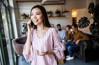 Güzel genç kadın iş adamları bir sürü bulanık arka plan önünde bir metin mesajı göndermek için akıllı telefon cihazında bir uygulama kullanıyor