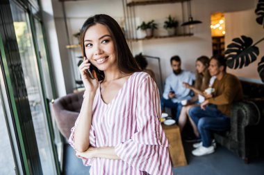 Güzel genç kadın iş adamları bir sürü bulanık arka plan önünde bir metin mesajı göndermek için akıllı telefon cihazında bir uygulama kullanıyor