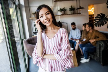 Gülümseyen güzel orta yaşlı iş kadını Closeup portre, kamera bakarak, sütun yaslanmış ve ışık ofis salonunda ayakta . Ön görünüm iş adamları arka plan 