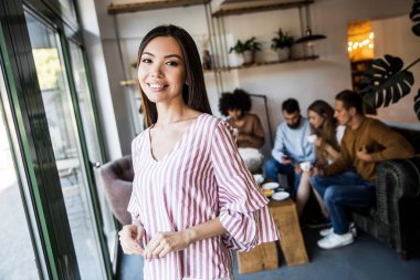 Gülümseyen güzel orta yaşlı iş kadını Closeup portre, kamera bakarak, sütun yaslanmış ve ışık ofis salonunda ayakta . Ön görünüm iş adamları arka plan 