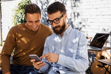 Genç hipster kardeşler akıllı telefon ile eğleniyor. En iyi arkadaşlar yeni trendler teknolojisi ile boş zaman paylaşımı. Çocuklar modern akıllı telefon cihazı ile bağlı 5g mesajlaşma günlük yaşam anları zevk