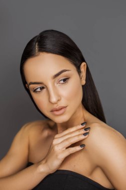 gri arka plan üzerinde uzağa bakan çekici gülümseyen esmer kız