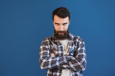 Kızgın sakallı hipster adam. Yaşam tarzı ve insan kavramı. Mutlu yakışıklı bir profesyonel. Sakal bakımı. Rahat gömlek stüdyoda mavi arka plan üzerinde sakallı Trendy gülümseyen hipster adam, kendinden emin 