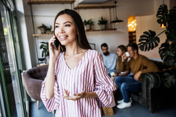 Güzel genç kadın iş adamları bir sürü bulanık arka plan önünde bir metin mesajı göndermek için akıllı telefon cihazında bir uygulama kullanıyor