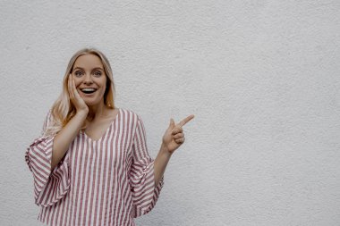 sokakta gri duvara yakın bir şey işaret çekici sarışın kadın şaşırttı