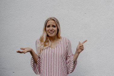 sokakta gri duvara yakın bir şey işaret çekici sarışın kadın şaşırttı