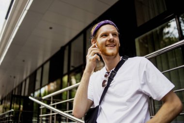 Yeni modern gadget telefon, cep, moda yakışıklı hipster adam elinde serin yeni uygulamalar ile akıllı telefon, kim ofisinin yakınında yürüyüş ve bazı iyi haber söylemek için birine çağrı. 