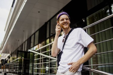 Yeni modern gadget telefon, cep, moda yakışıklı hipster adam elinde serin yeni uygulamalar ile akıllı telefon, kim ofisinin yakınında yürüyüş ve bazı iyi haber söylemek için birine çağrı. 