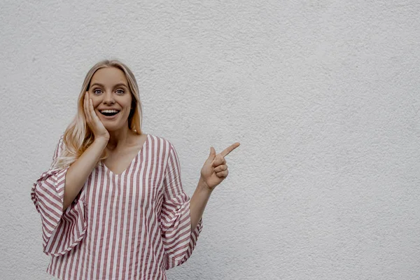 sokakta gri duvara yakın bir şey işaret çekici sarışın kadın şaşırttı