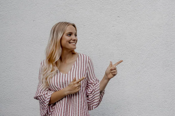 Sorrindo Atraente Mulher Loira Apontando Algo Perto Parede Cinza Rua — Fotografia de Stock