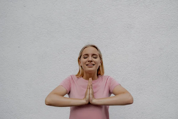 Lächelnde Attraktive Blonde Frau Betet Der Nähe Einer Grauen Mauer — Stockfoto