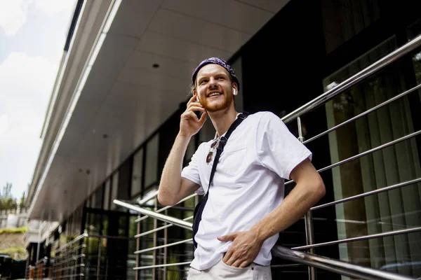 New modern gadget phone, cell, smartphone with cool new applications in hand of fashion handsome hipster man, who walking near his office and calling to someone to say some good news.