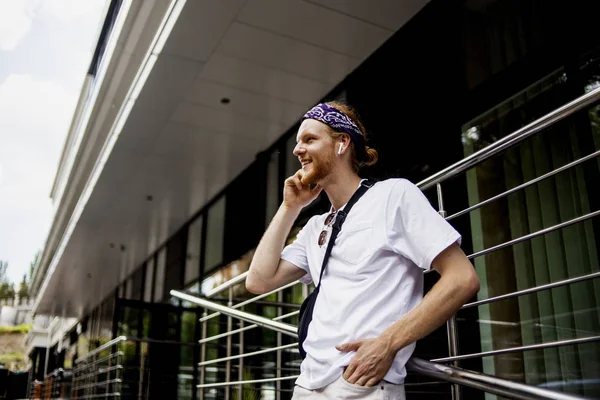 New modern gadget phone, cell, smartphone with cool new applications in hand of fashion handsome hipster man, who walking near his office and calling to someone to say some good news.