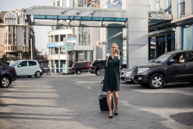 İş gezisi, iş için seyahat, ofis tarzı başarılı kadın şehir Havaalanı yürüyüş, vip araba kiralama hizmeti bekliyor ve cep telefonu internet arama.