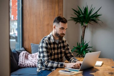 Yetişkin şık sakallı hipster adam sokak şehir Cafe shoo pencere yanında oturan, kendi bilgisayarda internet pazarlama online çalışan, meşgul ve konsantre kavramı