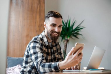 Kendinden emin akıllı meşgul freelancer internette sunum için net arama bilgileri sörf yaparken akıllı telefon uygulama yükleme kontrol modern teknolojileri kullanarak uzak iş yapıyor 