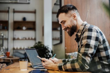 Sunum için net arama bilgileri sörf yaparken akıllı telefon uygulama yükleme kontrol modern teknolojileri kullanarak uzak iş yapıyor trendy gömlek emin meşgul erkek freelancer