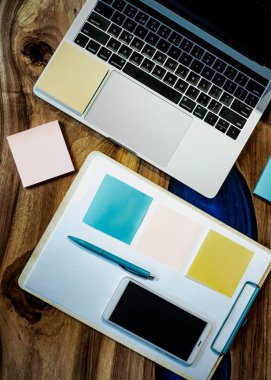 Düz yatıyordu, üst görünüm ofis masa masası. Ahşap masa arka planı üzerinde boş pano, klavye, ofis malzemeleri, kalem, renkli çıkartmalar ve cep telefonu ile çalışma alanı. - Resim