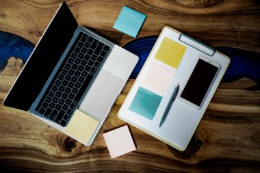 Düz yatıyordu, üst görünüm ofis masa masası. Ahşap masa arka planı üzerinde boş pano, klavye, ofis malzemeleri, kalem, renkli çıkartmalar ve cep telefonu ile çalışma alanı. - Resim