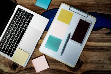 Düz yatıyordu, üst görünüm ofis masa masası. Ahşap masa arka planı üzerinde boş pano, klavye, ofis malzemeleri, kalem, renkli çıkartmalar ve cep telefonu ile çalışma alanı. - Resim