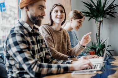 Onların proje hakkında tutkulu. Akıllı gündelik giyimli bir grup genç, yaratıcı ofiste otururken gülümseyerek birlikte çalışıyor. Yönetici bir soru jesti ve kamera görünümlü sahip 
