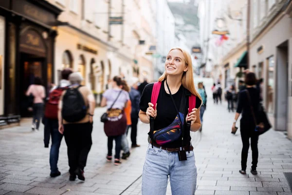 Look here! An impressed female tourist walks through a new city in a new country after a first flight. This is her first tour with a new tour operator. Fascinated by the sights of the city.