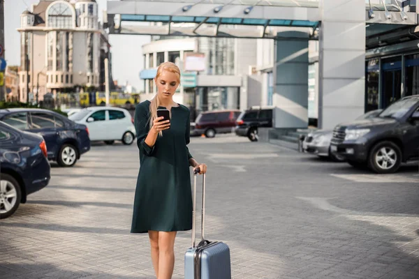 Business trip, traveling for work, office style successful woman walking urban Airport, waiting for vip car rental service and searching internet on cell phone.