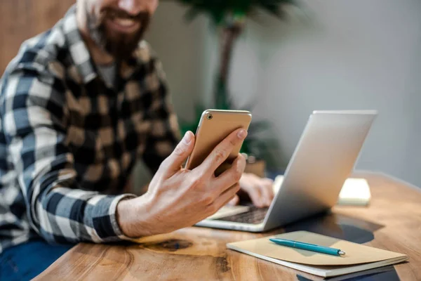 Modern iç sokak kafede akıllı telefon kullanan adam eli, cep telefonu ve online teknolojileri kullanan meşgul iş adamı, genç erkek öğrenci nin telefonunda oturan tahta masada oturan elinin üzerine odaklanın 