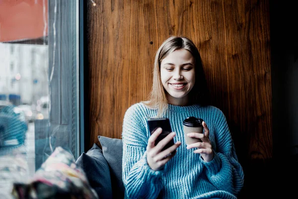 微笑的女人在社交网络上搜索照片 在当地咖啡馆喝咖啡 坐在窗户附近 放松和平静的心情 — 图库照片