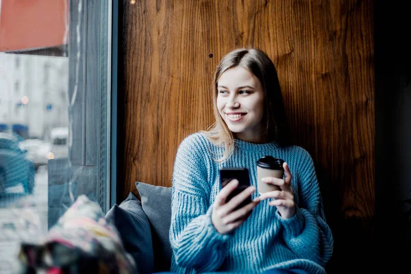 ソーシャルネットワーク上の写真を検索する幸せな笑い若い美しい女性 地元のカフェショップでコーヒーを飲む 窓の近くに座って リラックスして 穏やかな気分 — ストック写真