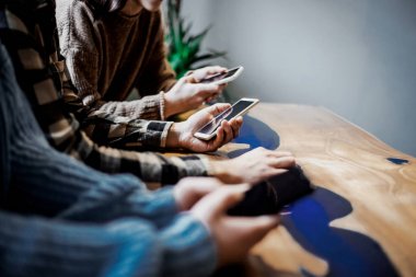 Bir grup arkadaş akıllı cep telefonlarını izliyor. Gençler yeni teknoloji trendlerine bağımlı. Gençlik, teknoloji, sosyal ve dostluk kavramı. Merkez ellere odaklanın. Akıllı telefon, hücre, ağ 