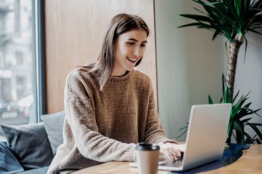 Modern kahve dükkanı sokak şehir kafede oturan modern teknolojileri kullanarak online çalışan güzel kadın blogger, dizüstü bilgisayar ve kahve fincan ı savuruyor. Bloglama, serbest çalışan, uzaktan çalışma