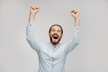 Gri arka plan üzerinde izole başarı yı kutlayan memnun bir genç adamın portresi. Dans ederken başarıyı kutluyoruz, boş kopya alanı. Çılgın duygusal, sevinç ve eğlence. İnanılmaz haberler