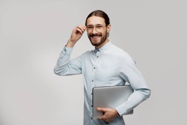 Şık Kafkas erkek metin yazarı trendy giysiler giymiş, serbest çalışır, dizüstü bilgisayarda bilgi türleri, kablosuz internete bağlı, özenli bir görünüme sahiptir, beyaz arka plan üzerinde izole