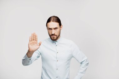 Izole gri arka plan üzerinde Genç yakışıklı adam memnuniyetini ifade eder ve üzgün ve korku ifadesi ile stop jest yapıyor. Utanmış ve olumsuz kavram. 