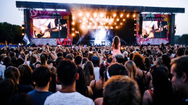 Müzik festivali dışında, kitlesel dünya etkinliği, sahnenin yakınında çok sayıda seyirci müzisyenin performansını dinliyor. Parlak renkler, yaz festivali, dans partisi, gerçek duygular