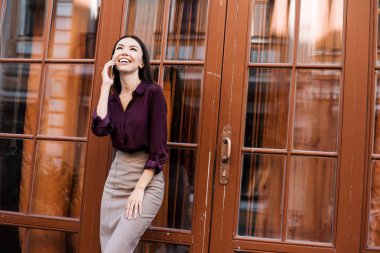 Boş zamanlarında kafenin yakınında tek başına yürürken cep telefonu yla arayan genç sevimli kadın, kafede dinlenirken telefonla konuşan sevimli gülümsemeli çekici kadın