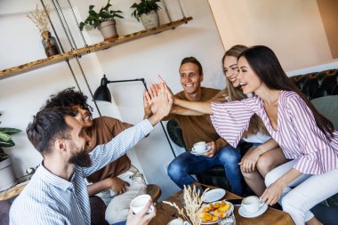 Modern bir kafenin iç mekanlarında oturan, birlikte eğlenen, kahve içen ve eğlenen bir grup genç