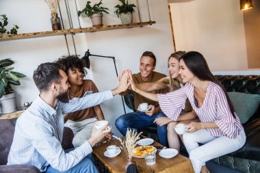 Modern bir kafenin iç mekanlarında oturan, birlikte eğlenen, kahve içen ve eğlenen bir grup genç