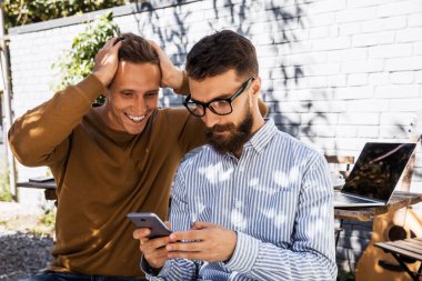Telefon ekranına bakan şaşkın yüz arkadaşlar. İki öğrenci, özel satış hattında mobil cihazlarla yüz ifadesini şaşırttı. İnanılmaz yeni teknolojiler ve yaşam tarzı kavramı
