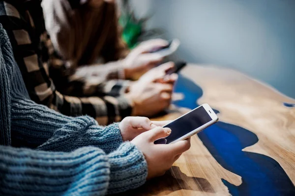 Group of friends watching smart mobile phones. Teenagers addiction to new technology trends. Concept of youth, tech, social and friendship. Main focus on center hands. Smartphone, cell, networking