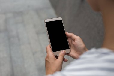 Uygulama, logo veya kopya hakkındaki bilgi içeriğiniz için boş kopyalama alanı ekranı olan akıllı telefonu tutan kadın ellerinin kırpılmış çekim görünümü, kentsel ortamda cep telefonundan metin mesajı okuma